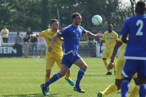 Billericays Rob Swaine (blue) clears from Billy Crook