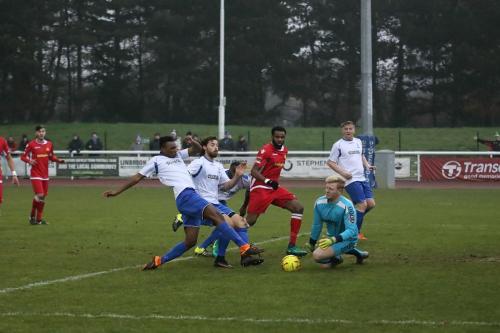Enfields Karl Oliyide (white, L) gets a toe to the ball ahead of keeper Josh Smith but Marc Okoye (red) is able to get back to clear off the line