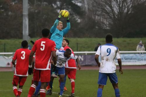 Merstham keeperr Josh Smith beats Percy Kiangebeni to a cross