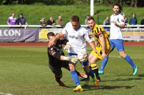 Folkestone keeper Tim Roberts just manages to knock the ball away from Scott Shulton