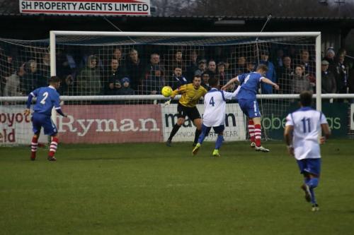 Needhams Billy Holland (blue,R) just manages to divert the ball away from Scott Shulton