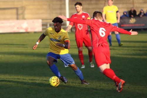 Enfields Dernell Wynter (yellow) runs past Joshua Webb