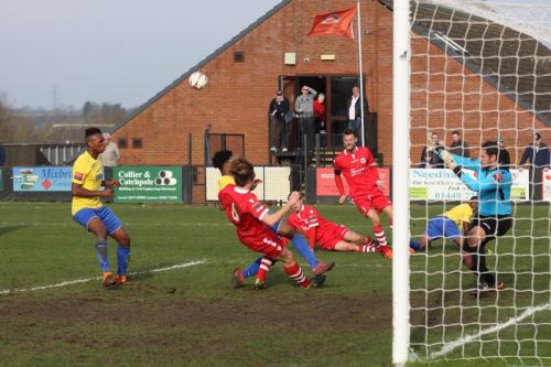 A cross from Ricky Gabriel (yellow, R) is cleared by the Needham defence