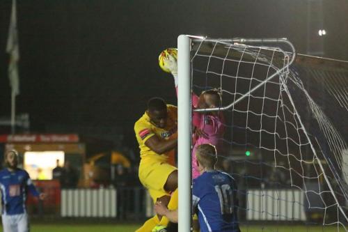 Enfields Harold Joseph (yellow) bundles keeper Anthony di Bernardo into the net