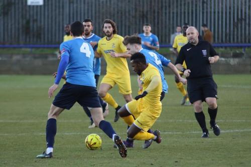 Wingates Alfie Young (blue, R) challenges Bobby Devyne