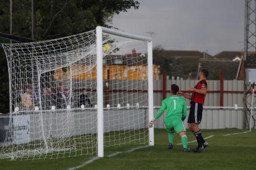 Brightlingsea keeper Sam Cowler and Jake Gould can only watch as Simon Thomass header bounces into the roof of the net