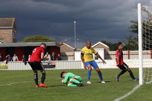 Brightlingsea keeper Sam Cowler makes sure the ball  doesnt run free for Simon Thomas (yellow)