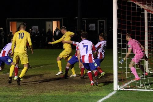Enfields Liam Hope (yellow, R) tries to backheel the ball towards goal but is crowded out by the defence