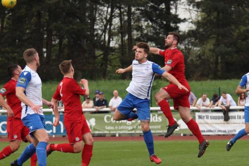 Worthings Aaran Racine (red, R) heads clear from Dan Rumens