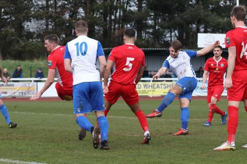Billericays Liam Hughes (red, L) blocks Dan Rumens shot