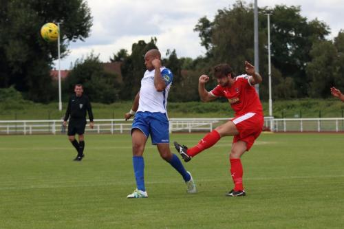 Folkestones Matthew Newman (red) clears from Simon Thomas