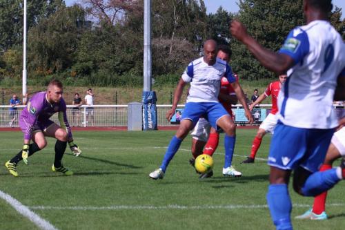A Harlow defender (red) gets a foot in to deny Simon Thomas