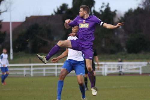 Tootings Sam Flegg (purple) heads clear from Simon Thomas