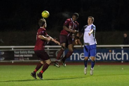 Wingates Ola Williams (centre) heads clear from Elliot Benyon watched by Sean Cronin