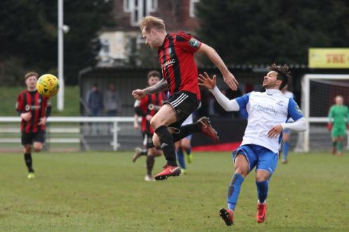 Brightlingseas Jake Gould heads clear from Tyler Campbell (R)