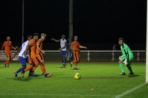 Enfields Montell Moore (white, R) rolls a shot across the six-yard box