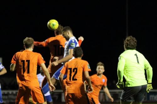 Enfields Taylor McKenzie (white) heads the ball goalwards  The ball was played back to him to score the last-minute equaliser
