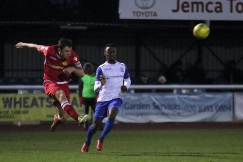 Mersthams Ben Harrison (L) clears from Ryan Blake