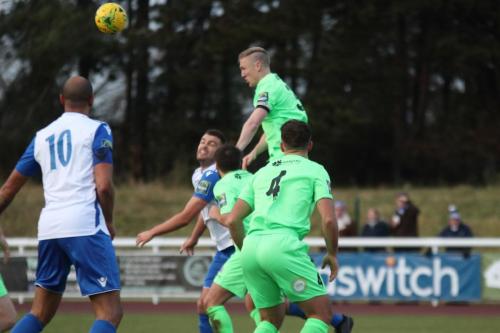 Dorkings Chris Boulter (green, rear) heads clear from Taylor McKenzie