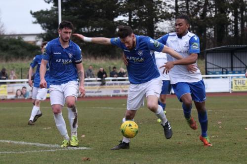 Enfields Dernell Wynter (R) challenges Rory McAuley as Travis Cole looks on