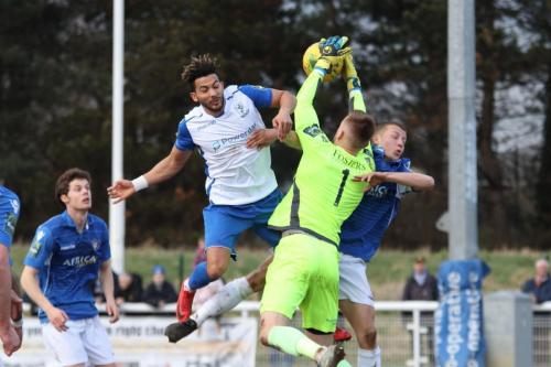 Lowestoft keeper Ben Dudzinski collects under pressure from Tyler Campbell  Dudzinskis team mate Dan Humphreys (R) doesnt make it any easier