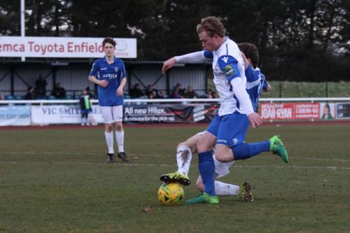 Lowestofts Harvey Hodd (blue) gets a foot in just in time to prevent Aaron Greene from getting a clear shot