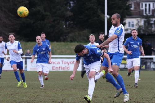 Lowestofts Travis Cole (blue) heads clear from Simon Thomas