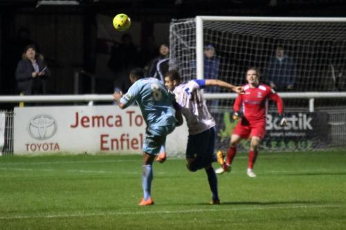 Enfields Taylor McKenzie heads the ball away from Dennis Oli (L)