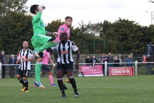 Hanwell keeper Xavi Comas punches clear from Dan Rumens (pink)