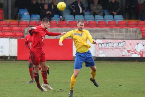 Harrows Adam Richards (red) heads clear from Brad Wadkins