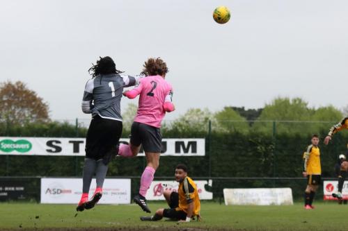 Merstham keeper Ashlee Jones punches clear from Mickey Parcell