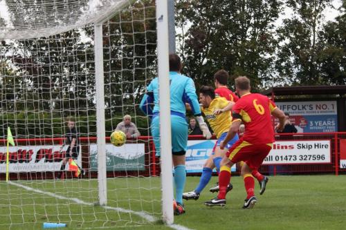 Enfields Drew Roberts (yellow) punches the ball wide of the post to earn a yellow card