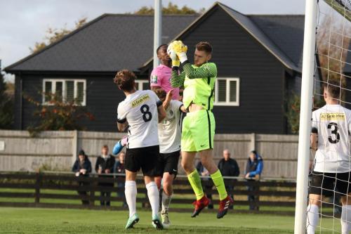 Royston keeper Joe Welch catches under pressure from Gus Scott-Morriss and Enfields Ryan Blake (pink)