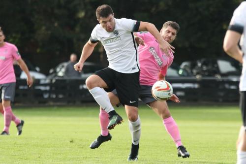 Roystons John Frendo (white) lays the ball off under pressure from John Kyriacou