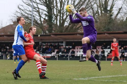 Hornchurch keeper Callum Chafer catches the ball as George Winn (red) keeps Sam Youngs in check
