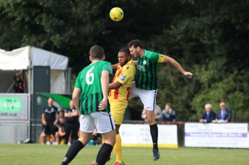 Burgess Hill captain Gary Elphick (R) wins a header against Taofiq Olomowewe