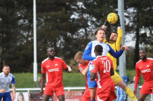 Carshalton keeper Billy Bishop catches under pressure from Sam Youngs