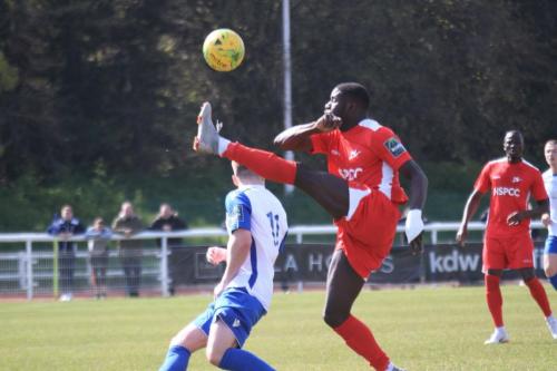 Carshaltons Jacob Mendy (red) clears from Josh Davison