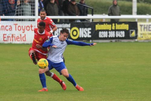 Mersthams Gus Sow clears under pressure from Sam Chaney (R)