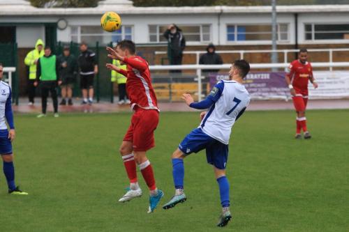 Mersthams Jake Hutchings (red) heads clear from Bilal Sayoud