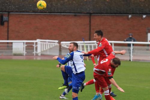 Mersthams Jake Hutchings (red 4) heads clear from Billy Bricknell