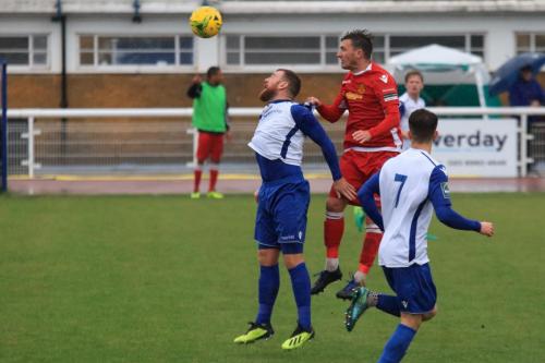 Mersthams Simon Cooper (red) heads clear from Billy Bricknell