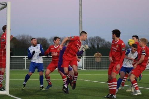 A header from Cahrlie Stimson (red, centre) rebounds goalwards and is blocked