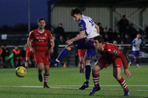 Enfields Josh Davison (white) beats Glenn Wilson to get a header towards goal