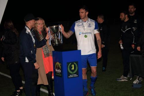Injured captain Ryan Blackman (L) and stand-in Matt Johnson collect the trophy