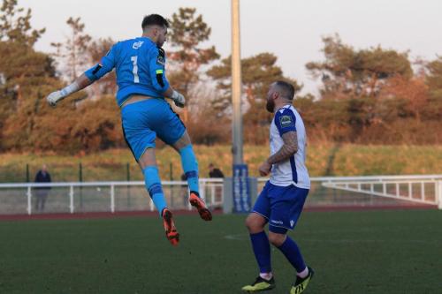 Folkestone keeper Tim Roberts heads clear from Billy Bricknell