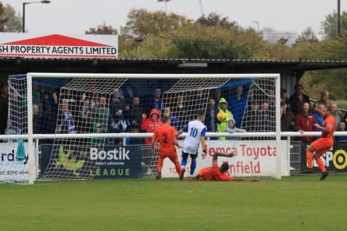 Wares Bradley Frasier (orange, centre) blocks Brandon Adams in from of an open goal