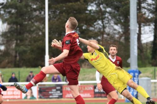 Bognors Chad Field (maroon) clears the ball before his keeper Petar Durin arrives