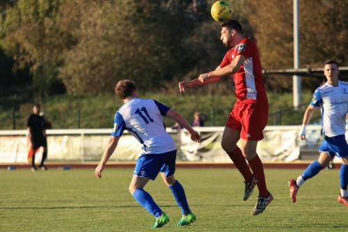 Whitehawks Matt Drage (red) heads clear from Aaron Greene