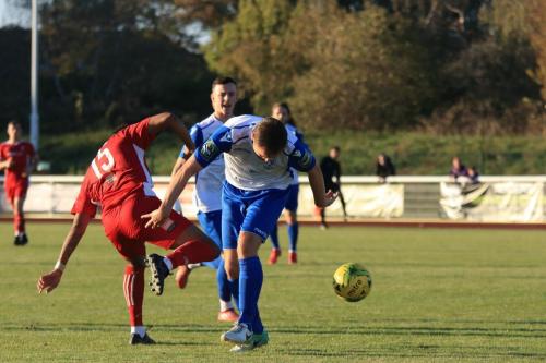 Whitehawks Ronayne Marsh-Brown (red) challenges Liam Hope  but the ball runs to Brandon Adams for the fifth goal